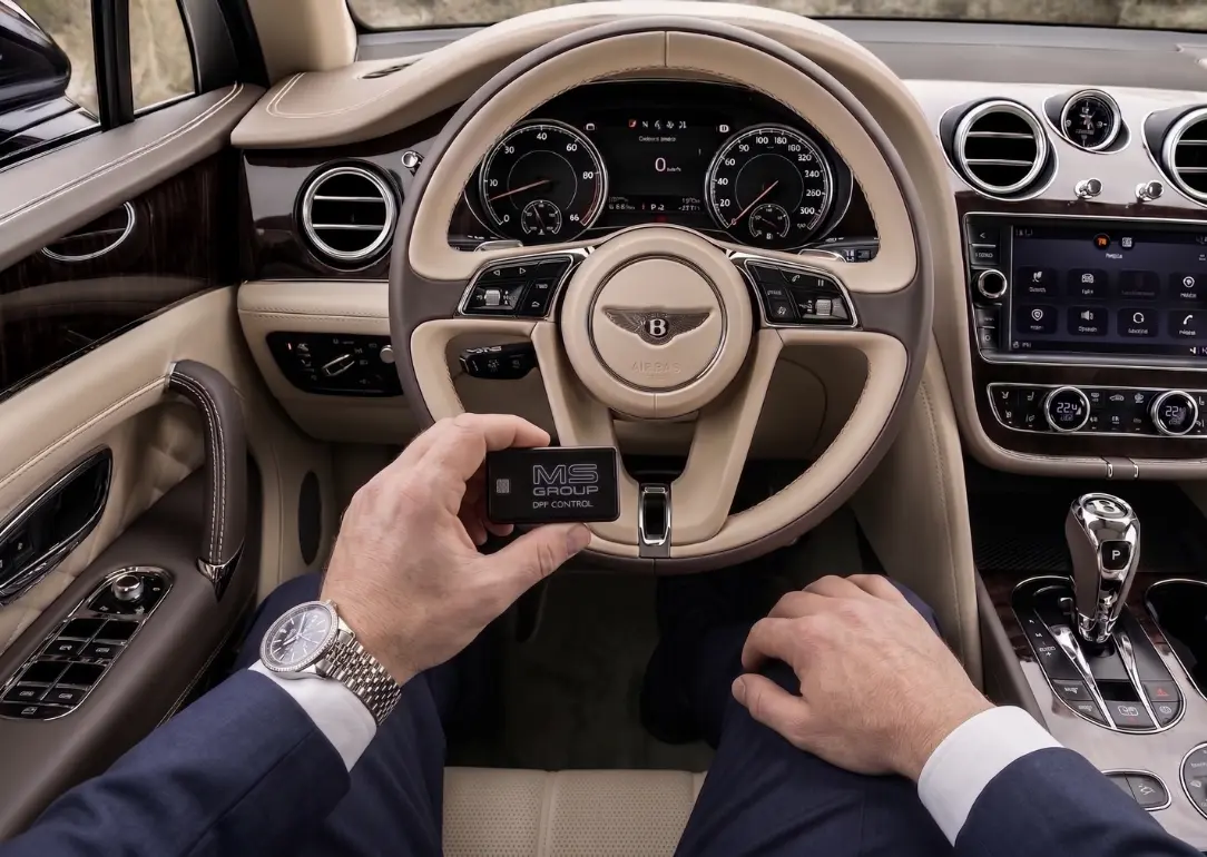 DPF Control module for Bentley vehicles held in hand against a car dashboard background